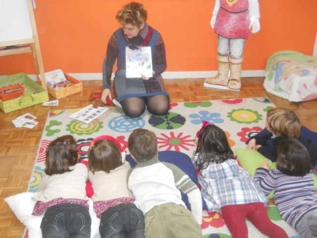 ninos tumbados en una alfombra viendo el cuento de una monitora